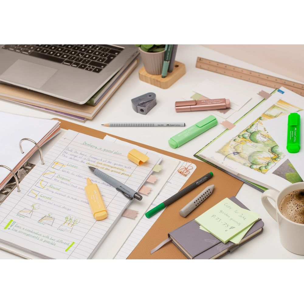 Scrivania con laptop, taccuino, penne, evidenziatori e una tazza di caffè.