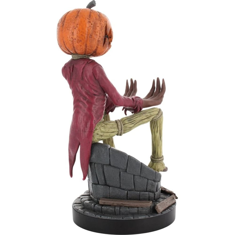 Una figura con cabeza de calabaza se sienta en el borde de un pozo. Lleva una chaqueta roja.