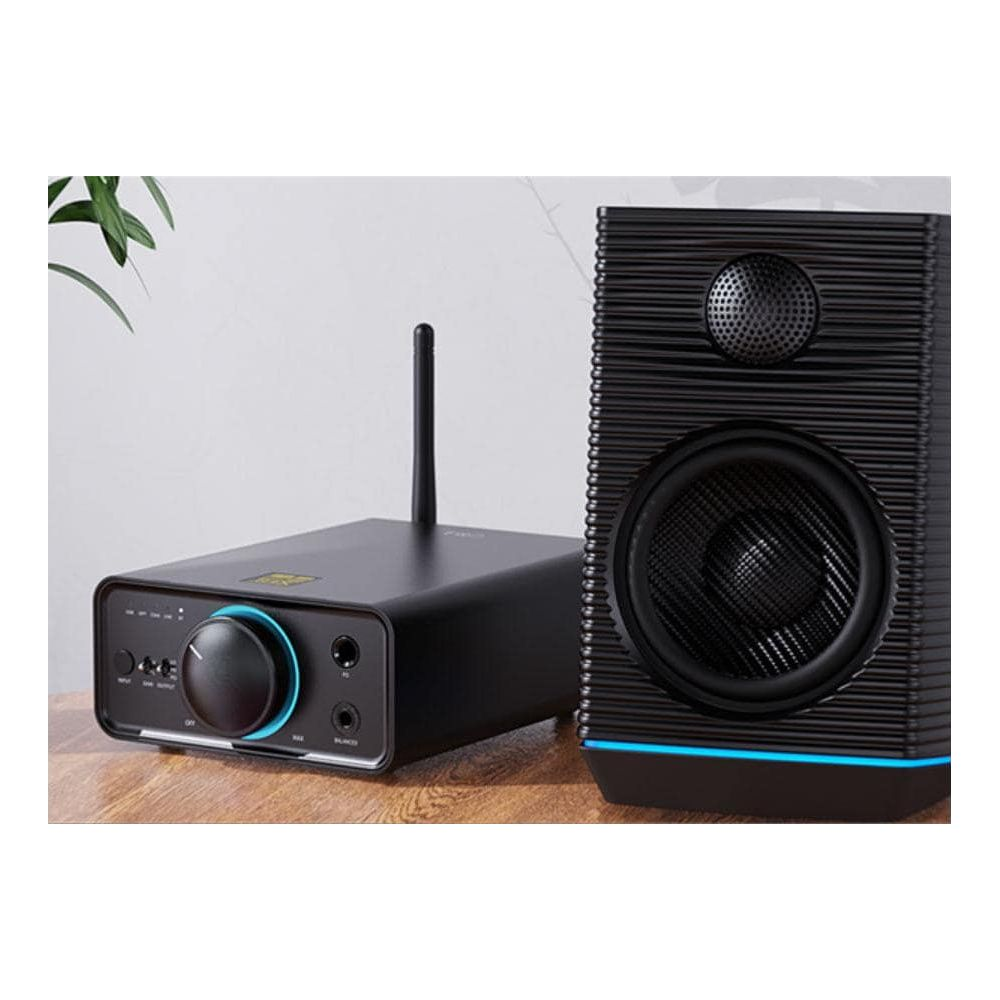 Amplificador negro con antena y altavoz con detalles azules sobre madera.