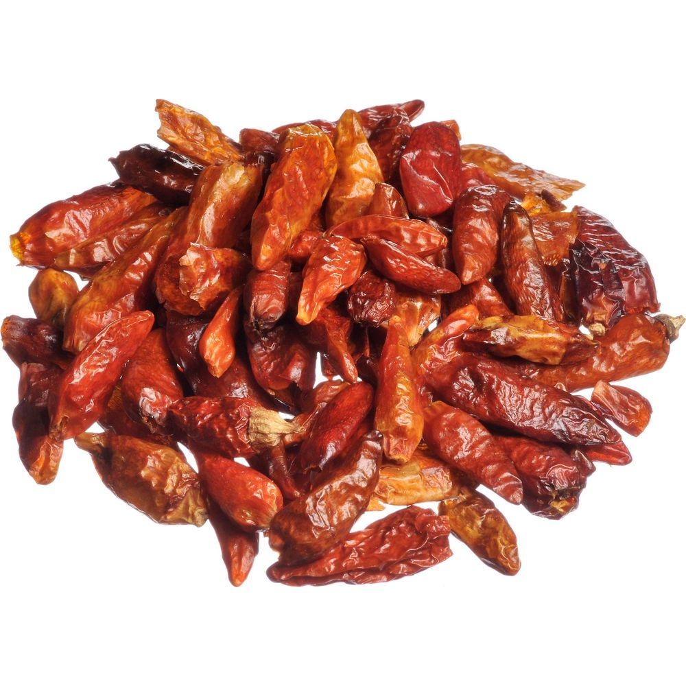 Ein Haufen kleiner, trockener, roter Chilis liegt auf weißem Hintergrund.