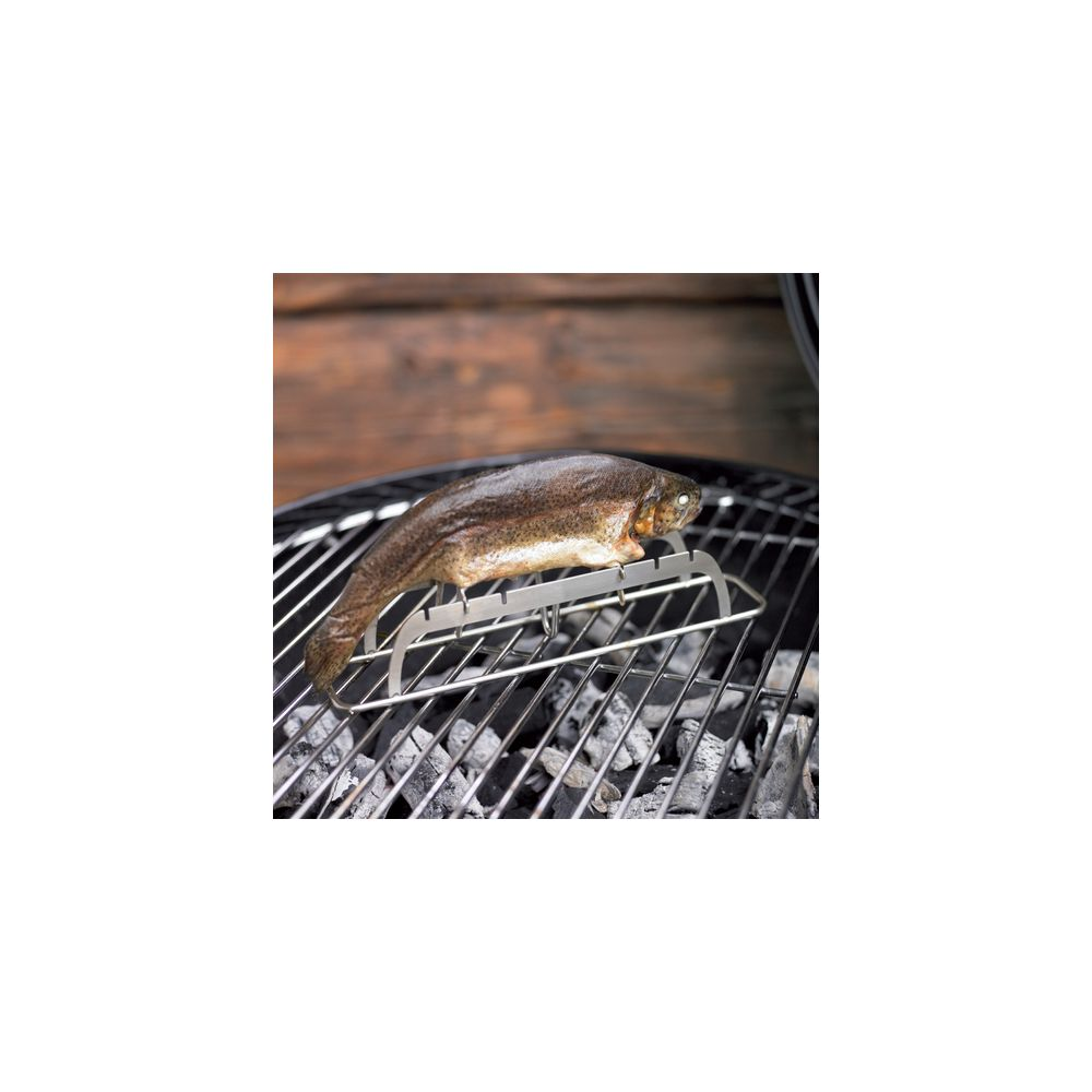 Ein Fisch wird auf einem Grillständer über glühenden Kohlen gegrillt.