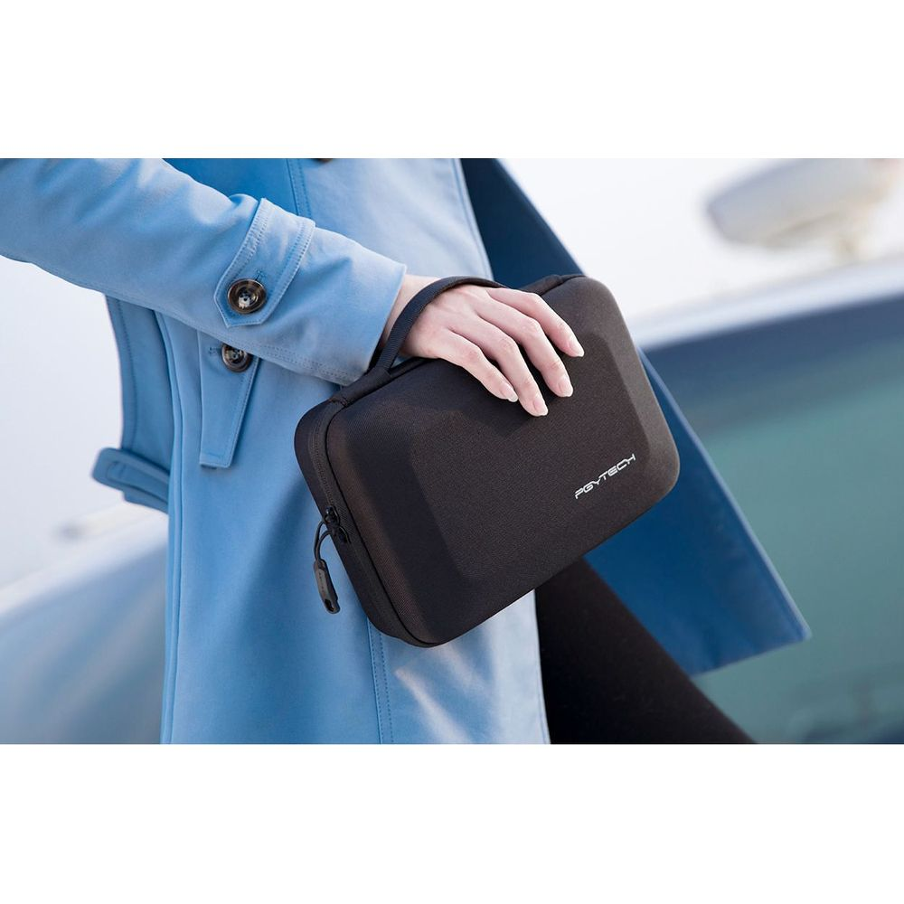 Una persona in cappotto blu tiene una borsa nera con manico.