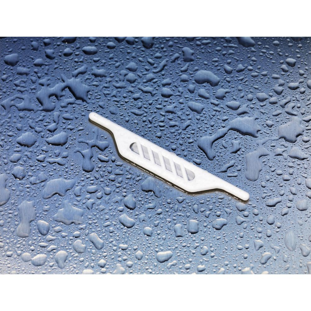 Un objet blanc avec des fentes repose sur une surface bleue et humide.