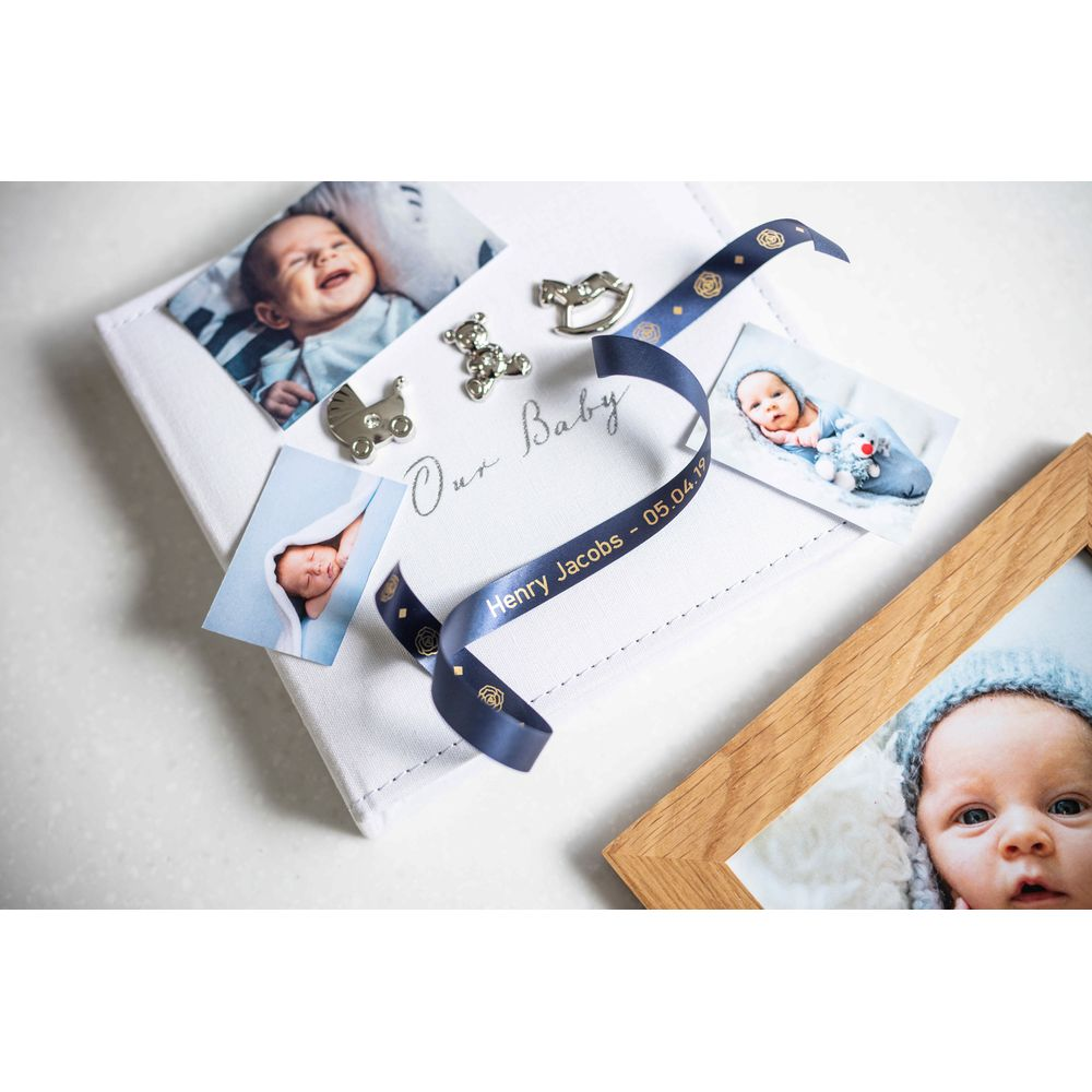 Babyalbum mit Fotos, Namensband und Deko.