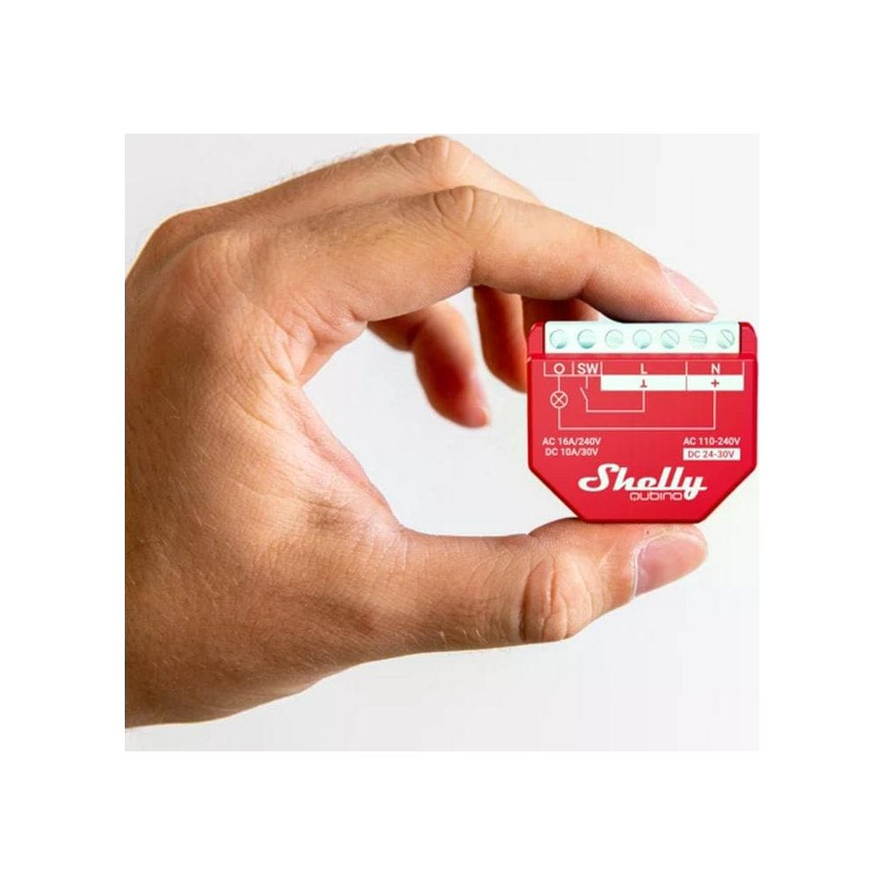 Una mano sostiene un pequeño dispositivo rojo Shelly con terminales y etiquetas.