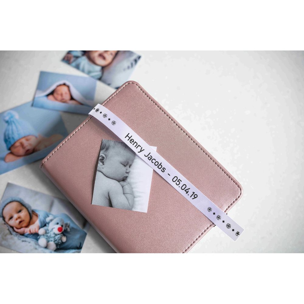 Rosa Notizbuch mit Babyfotos und Band mit Namen.