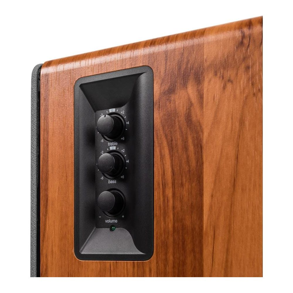 Zbliżenie drewnianego głośnika z czarnym panelem z pokrętłami tonów wysokich, basu i głośności.