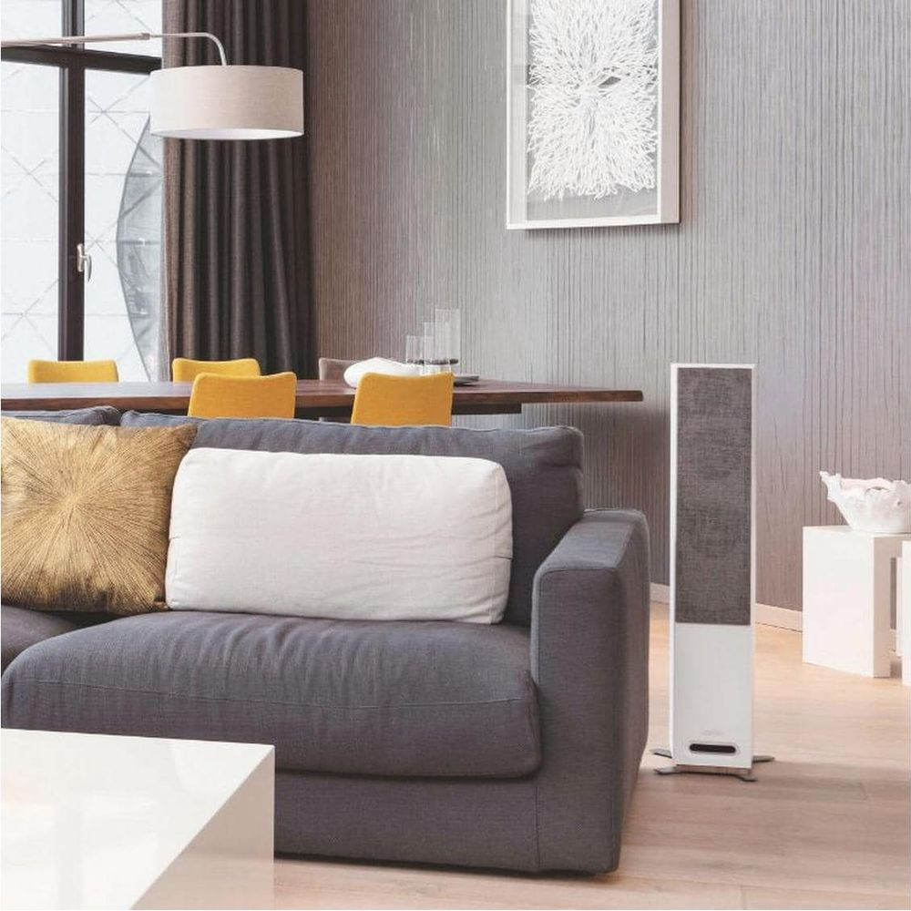 Ein modernes Wohnzimmer mit grauer Couch, gelben Stühlen und hohem Lautsprecher.