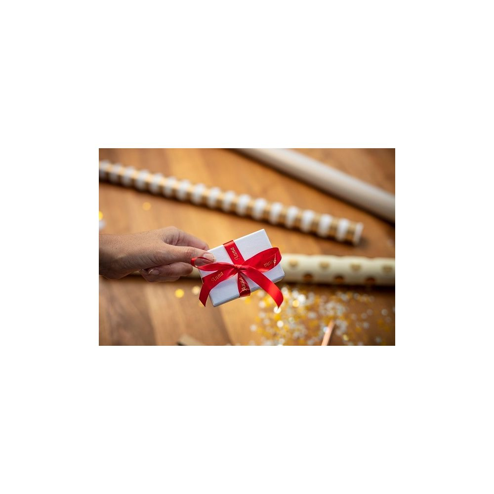 Eine Hand hält eine kleine weiße Geschenkbox mit rotem Band.