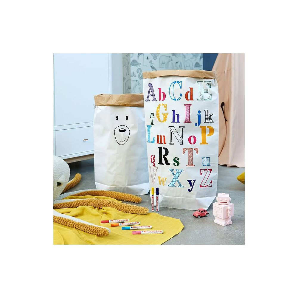 Zwei Papiertüten, eine mit Bärenmotiv, die andere mit dem Alphabet. Stifte und Spielzeug liegen daneben.