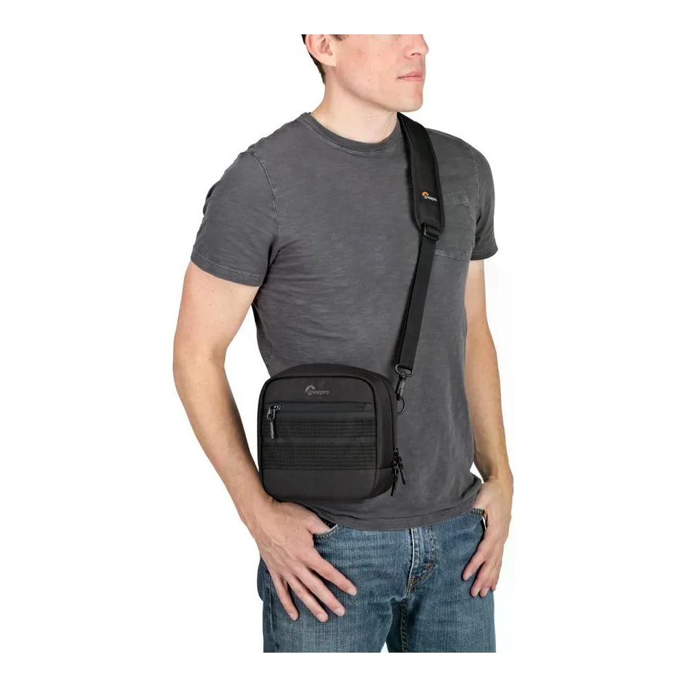 Mann mit grauer T-Shirt und Jeans trägt schwarze Umhängetasche.