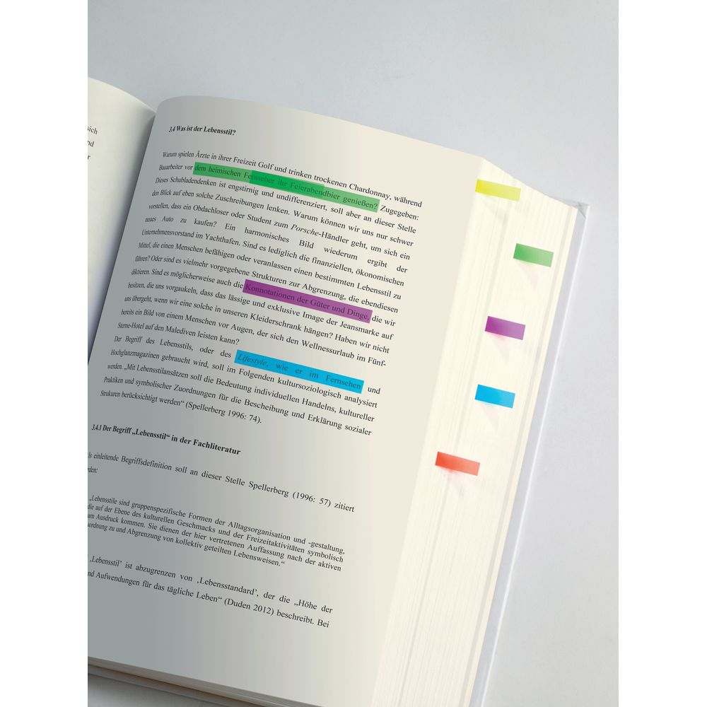 Ein offenes Buch mit Text und bunten Markierungen. Nahaufnahme.