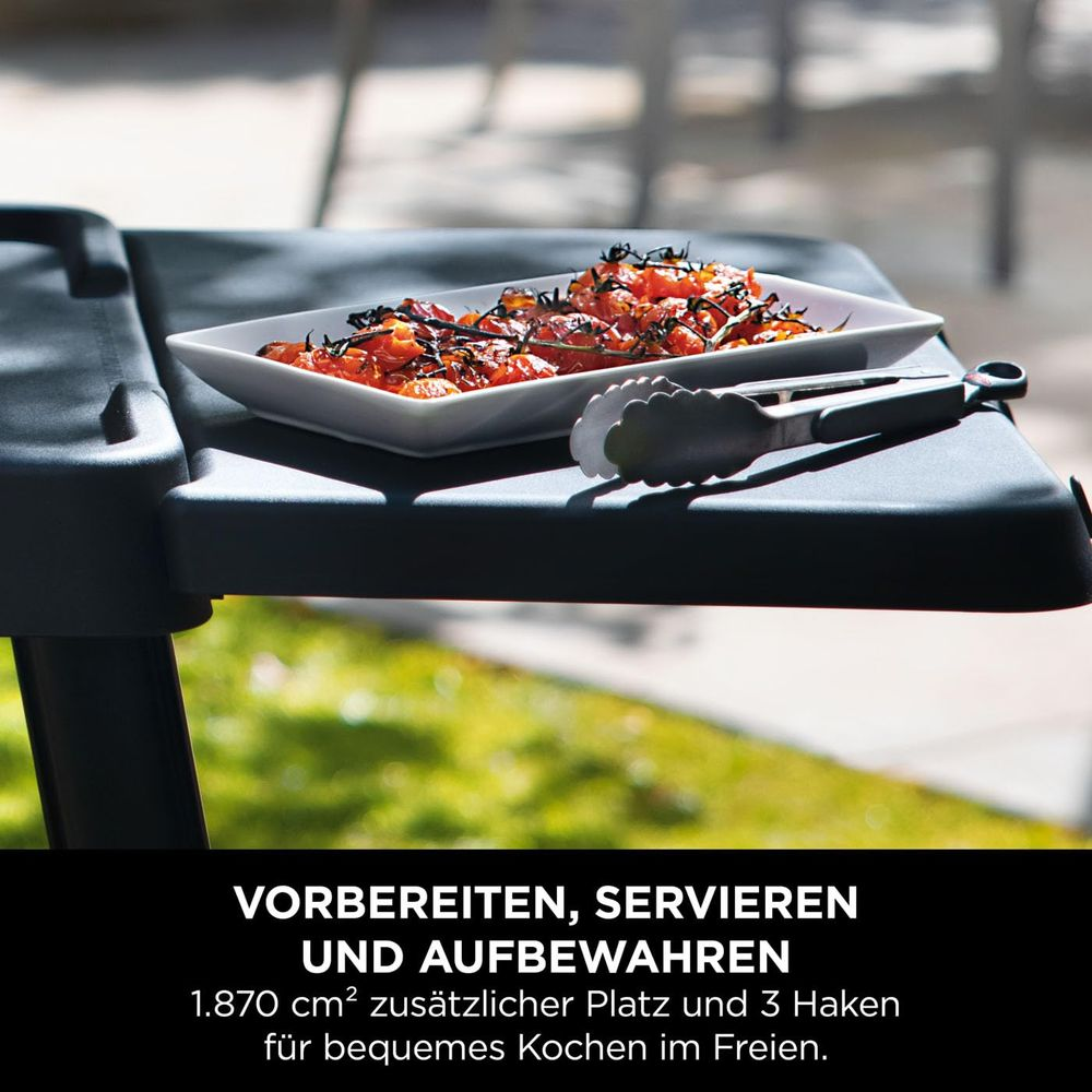 Gartentisch mit Schale voll gerösteter Tomaten und Zange.