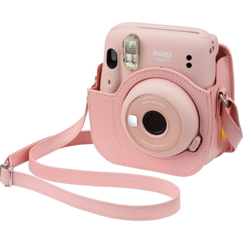 Een roze instantcamera met beschermhoes en riem.