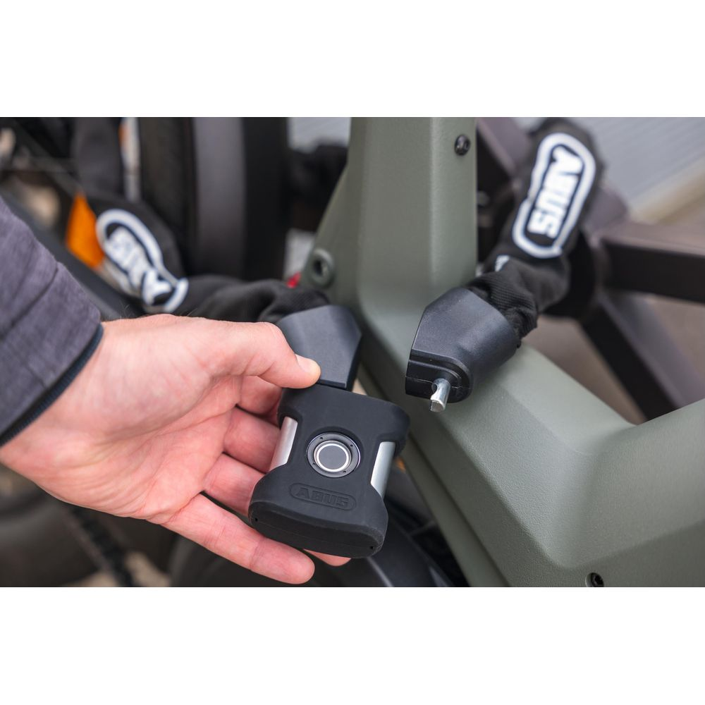 Eine Hand hält ein schwarzes Fahrradschloss mit Fingerabdrucksensor.