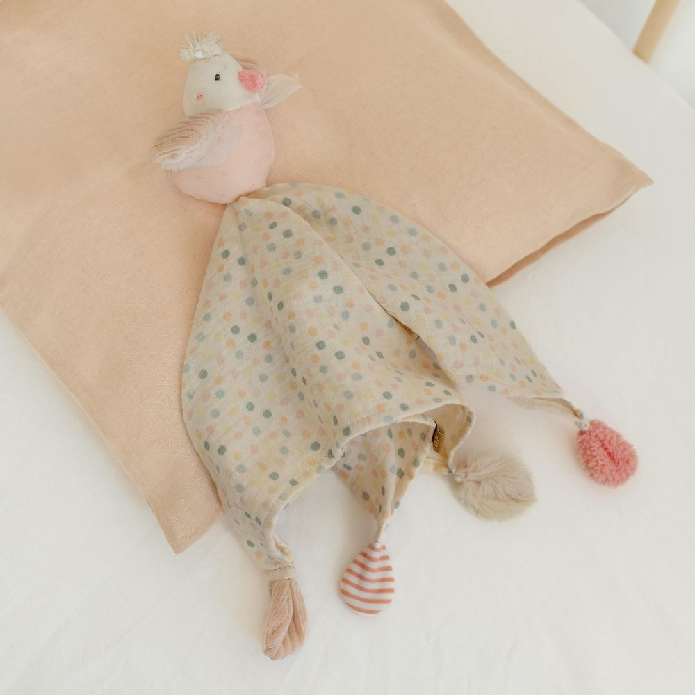 Une couverture de sécurité oiseau à pois de couleur pastel sur une couverture rose.
