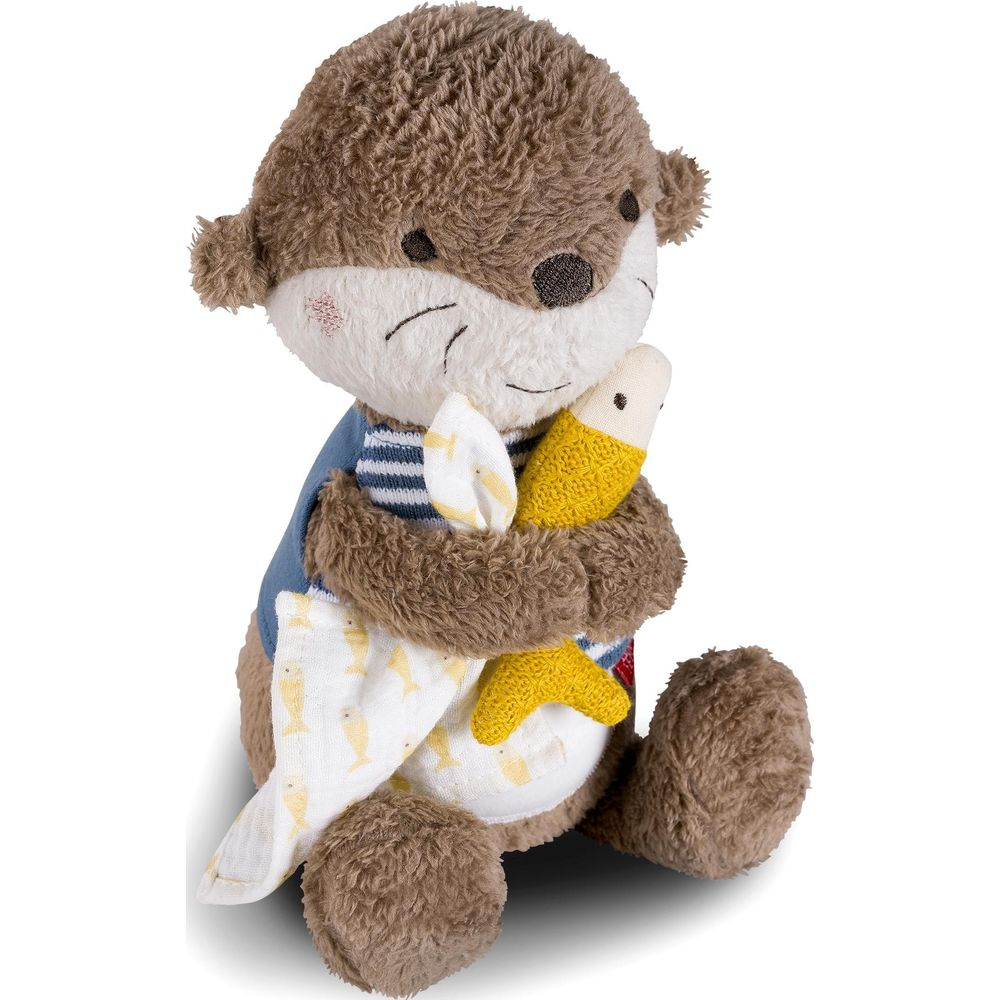 Une loutre en peluche portant une chemise bleue rayée tenant un poisson jaune.