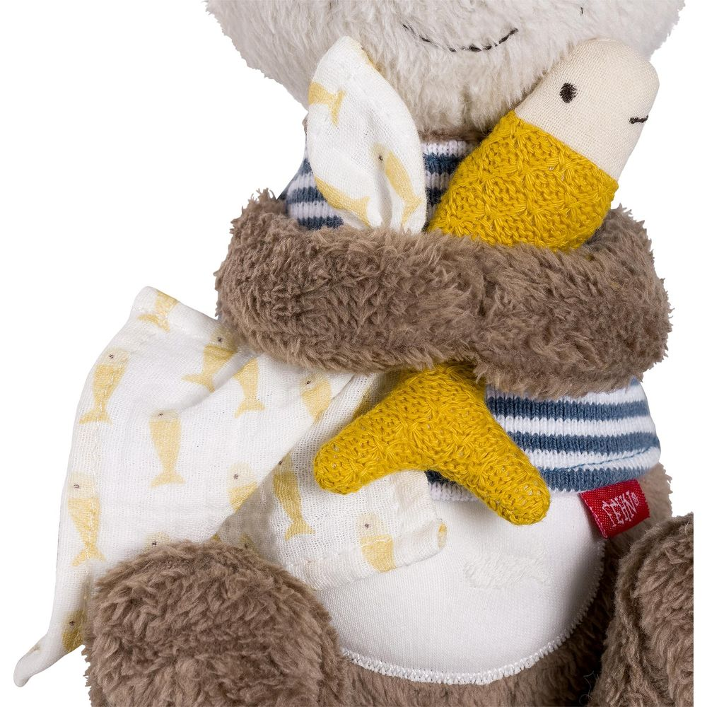 Un ours en peluche porte un haut rayé et une écharpe marron.