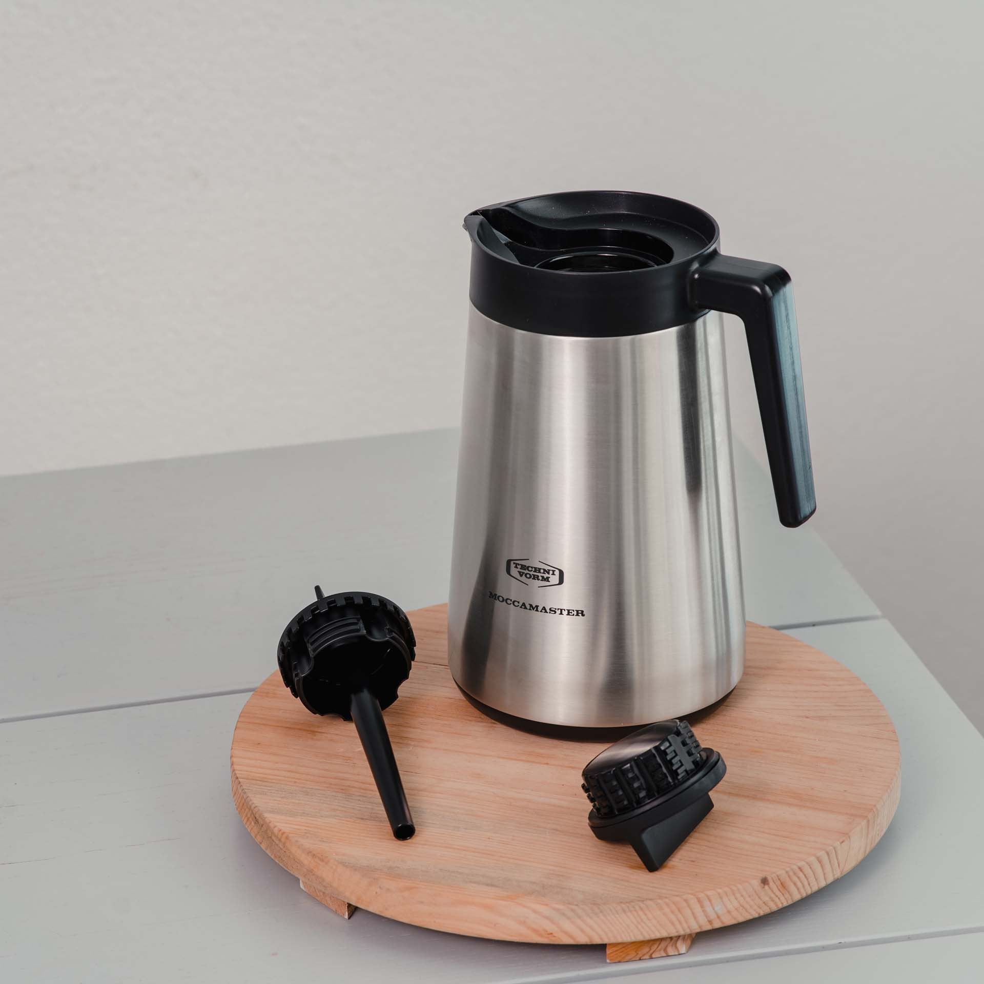 Silberne Thermoskanne mit schwarzem Griff und Deckel, daneben schwarze Teile.