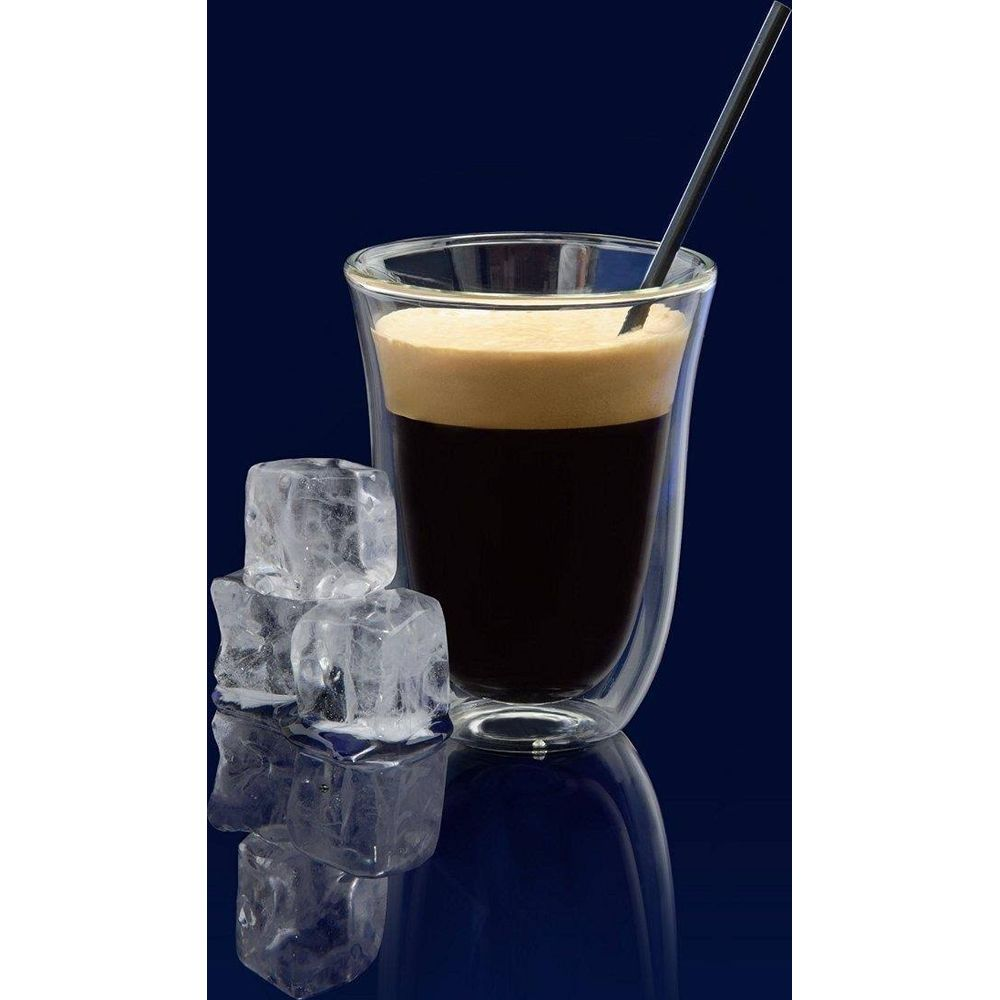 Un vaso de café con espuma, cubitos de hielo y una pajita sobre fondo azul.