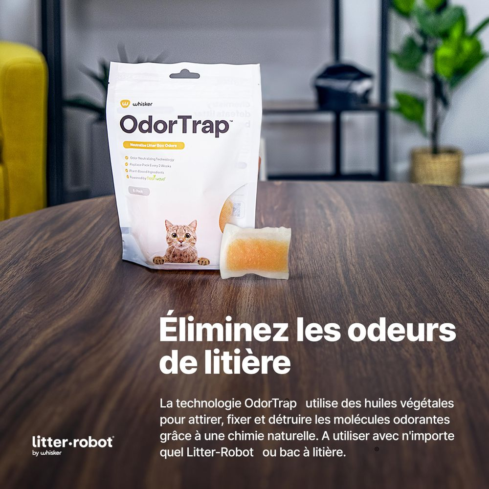 Un paquete de OdorTrap con un gato y un sobre en una mesa de madera.
