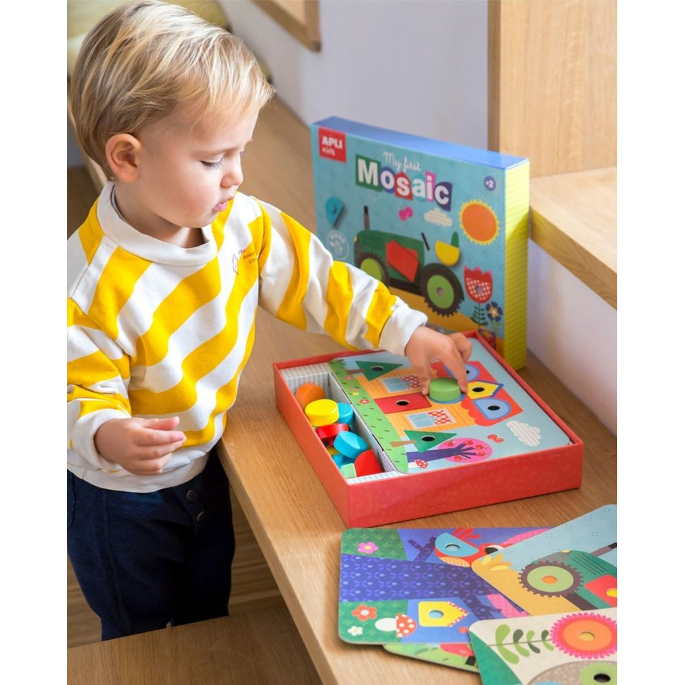 Un enfant joue avec un jouet mosaïque comportant des pièces en bois colorées.