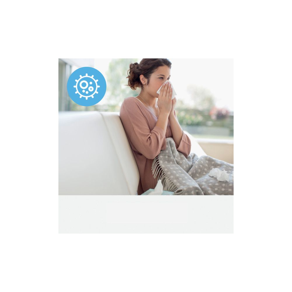 Kobieta z chusteczką przy ustach na kanapie, z grafiką wirusów obok.