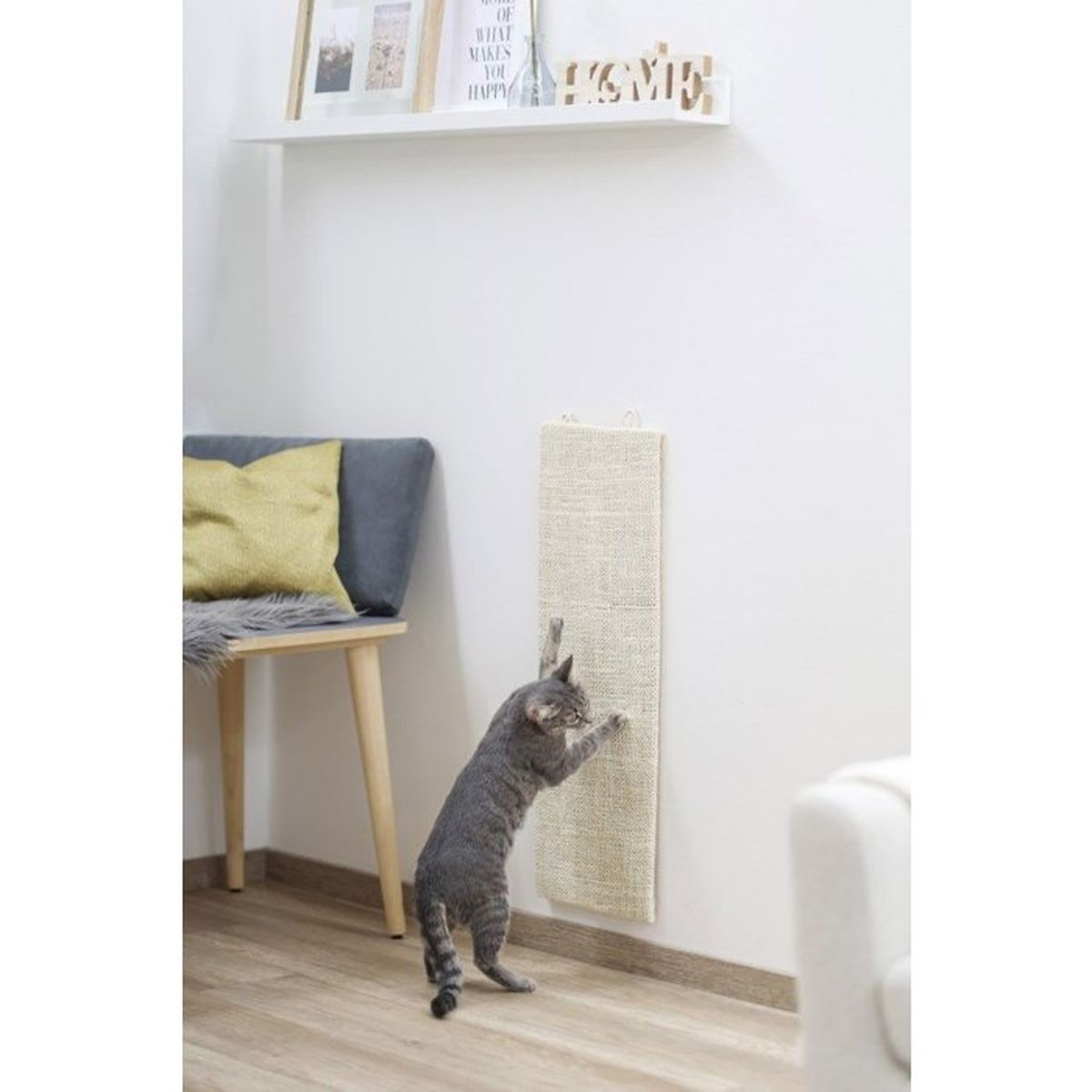 Un gatto si graffia su un tappetino graffiato beige a muro.