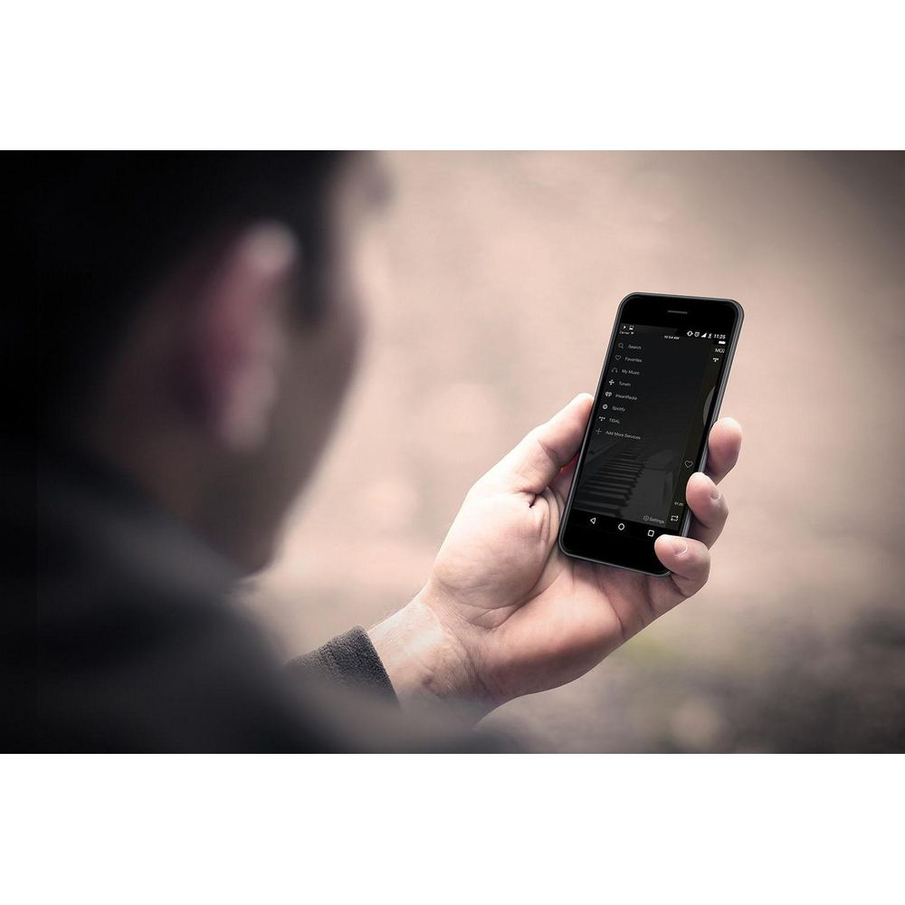 Hombre sostiene smartphone con app de música; teclas de piano como fondo.