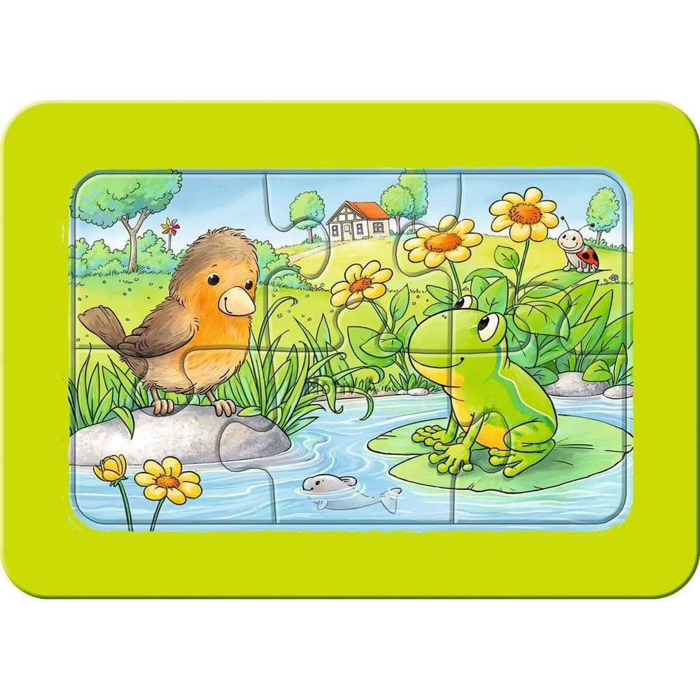 Ein Vogel sitzt auf einem Stein, ein Frosch auf einem Seerosenblatt.