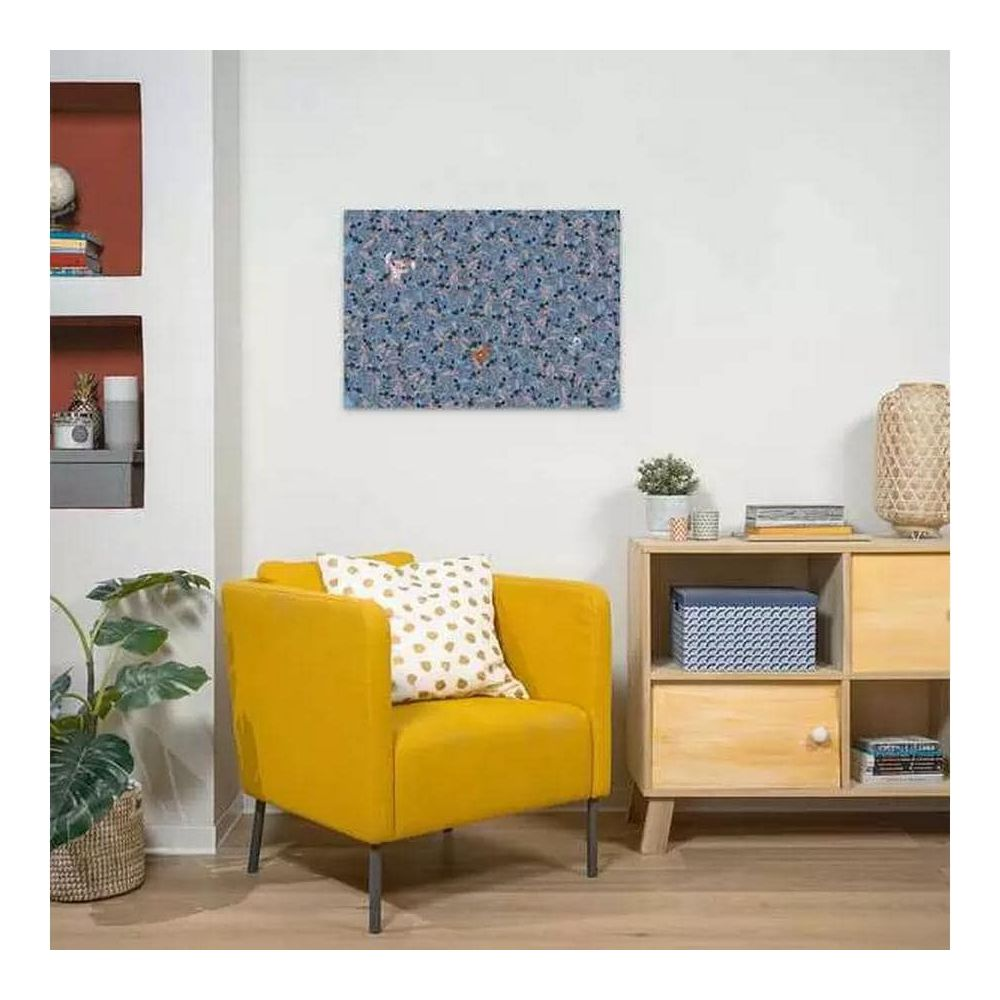 Un fauteuil jaune avec coussins devant une armoire. Un tableau d'animaux est accroché au mur.