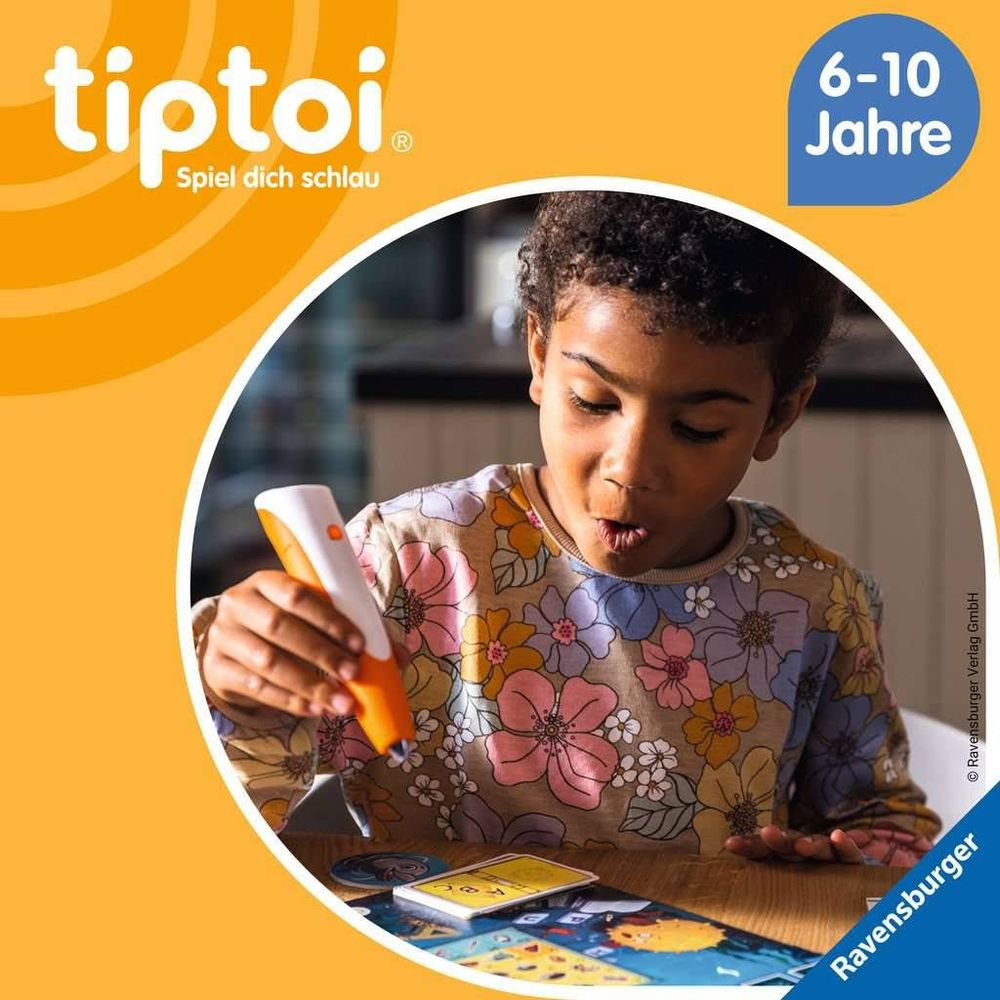 Un ragazzo gioca con una penna Tiptoi e carte su un tavolo.