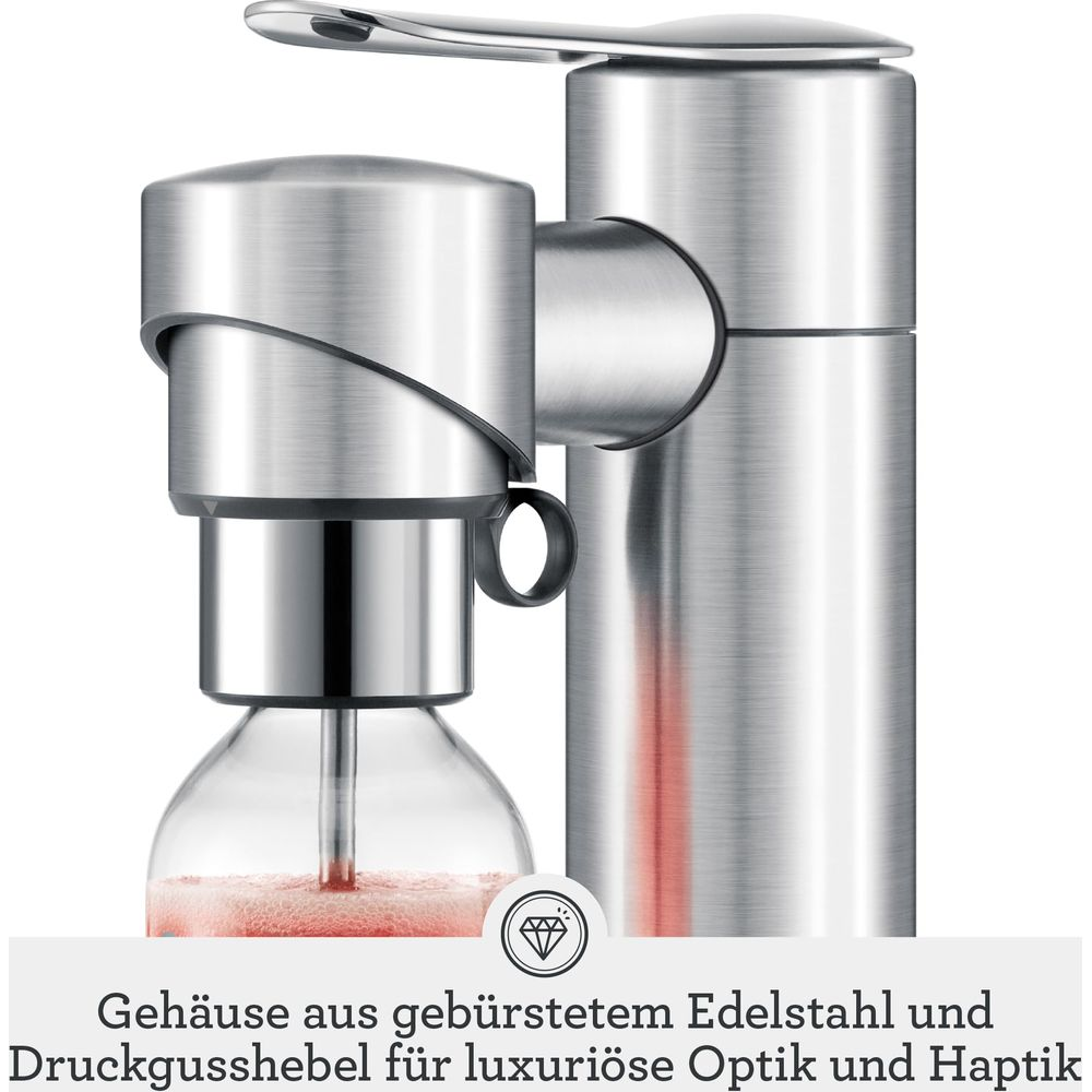 Gebürsteter Edelstahl-Wassersprudler mit Glasflasche und roter Flüssigkeit.