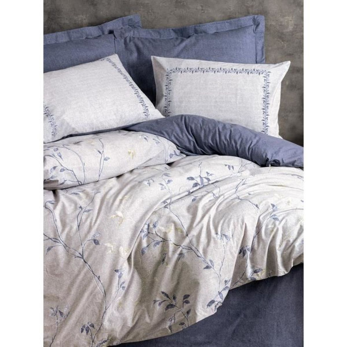 Ein Bett mit blauem und weißem floralem Muster, Kissen und Decken.