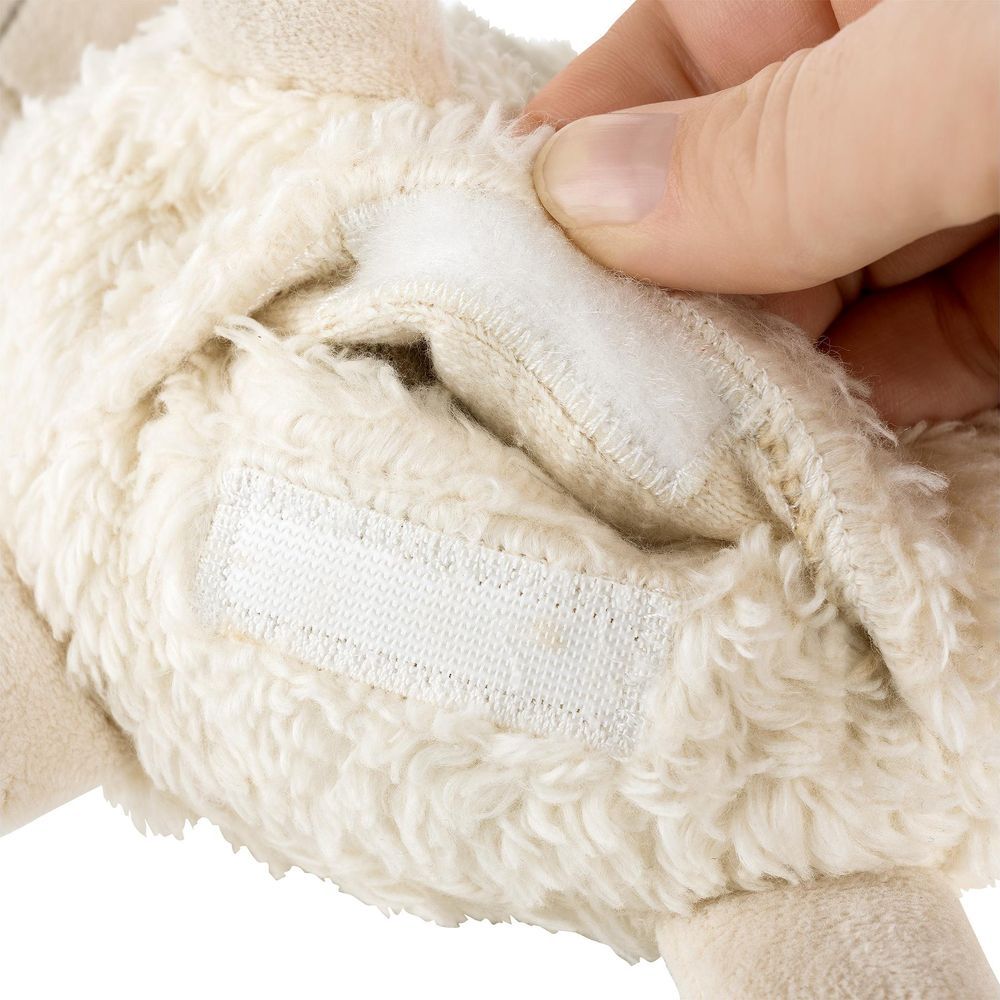Una mano apre una chiusura in velcro su un peluche color crema.