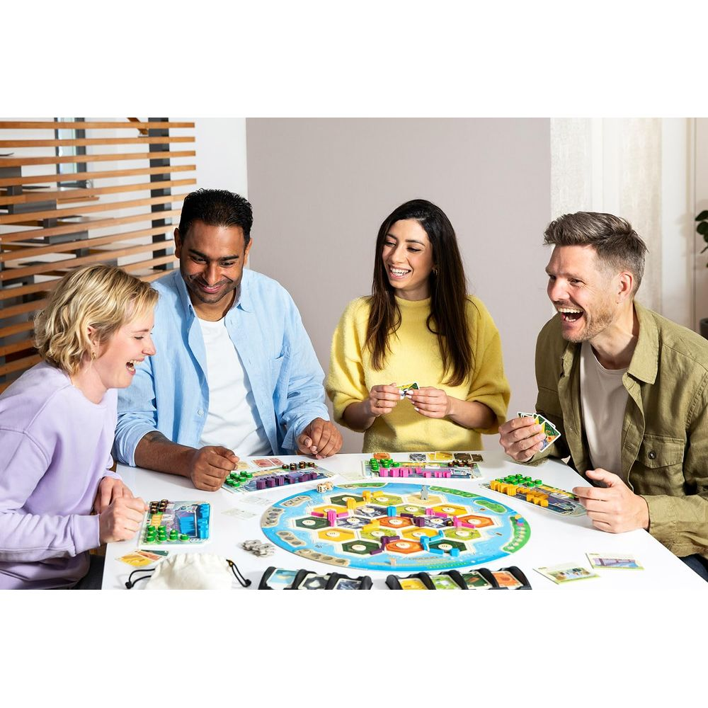 Vier lachende Personen spielen ein Brettspiel mit bunten Teilen auf einem runden Spielfeld.