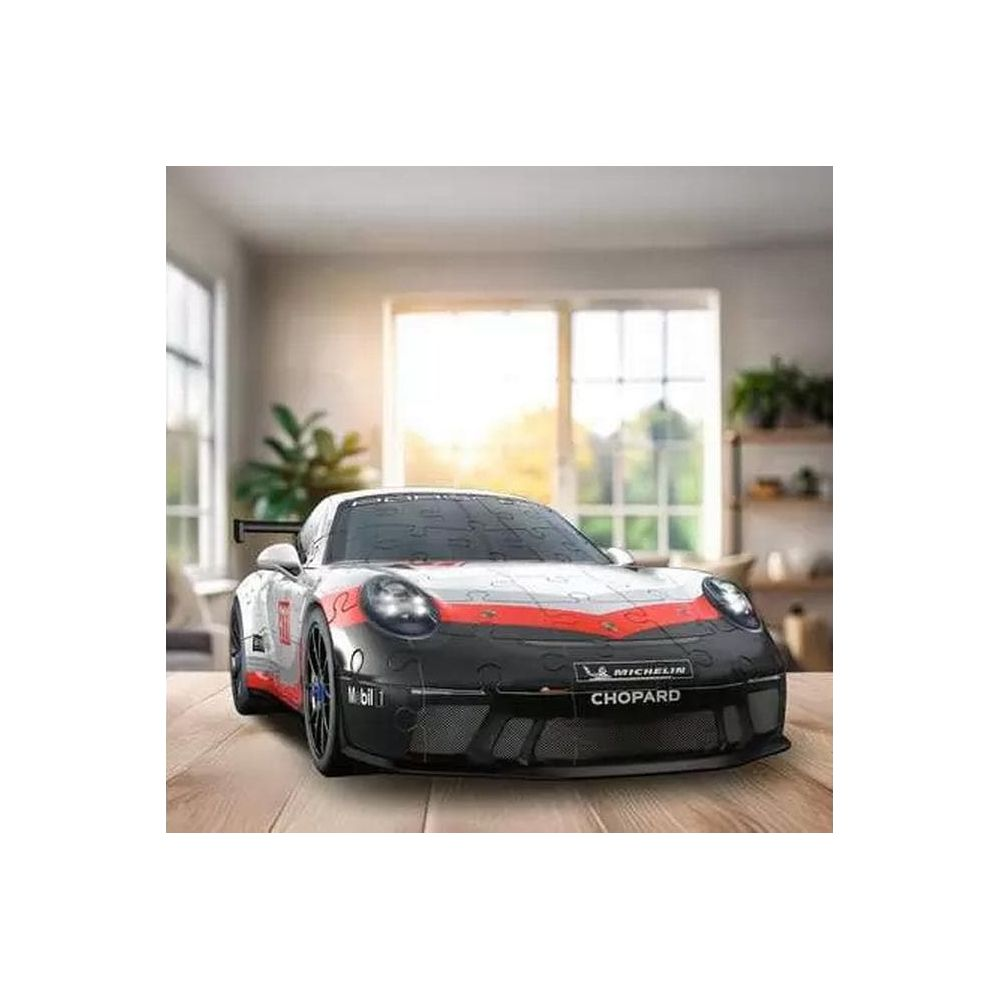 Ein Porsche-Puzzleauto in Schwarz und Rot steht auf einem Holztisch in einem hellen Raum.