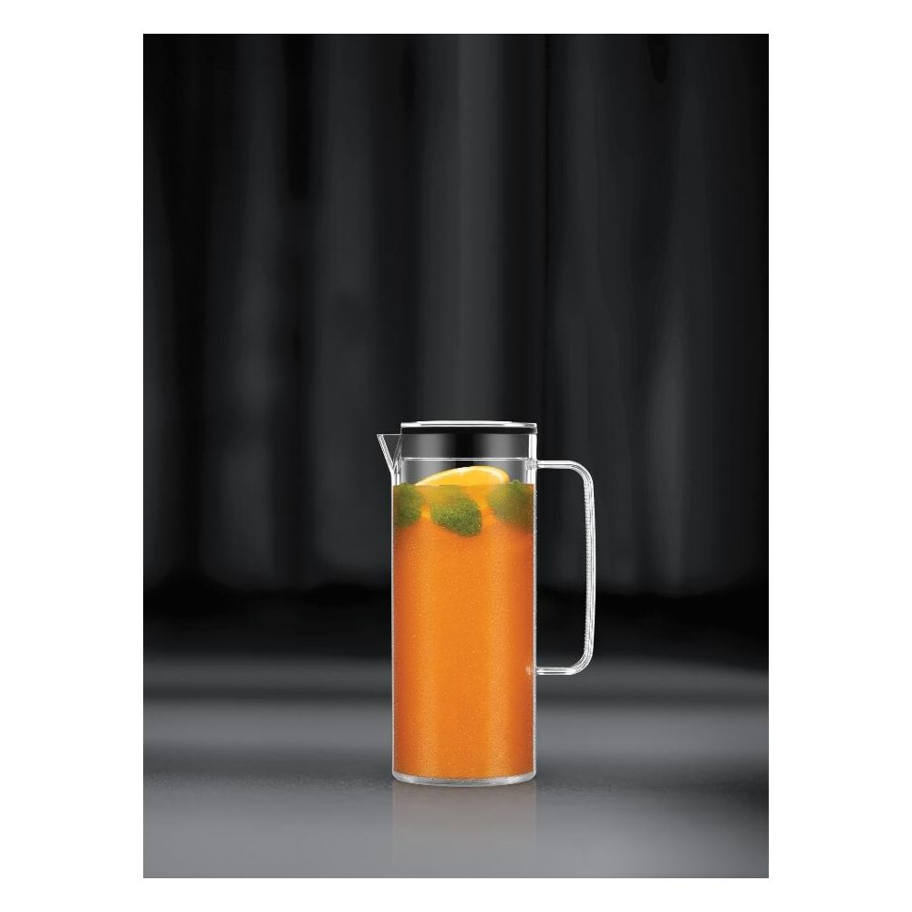 Eine Glas Karaffe mit orangem Saft, Minze und Zitrone auf dunklem Hintergrund.