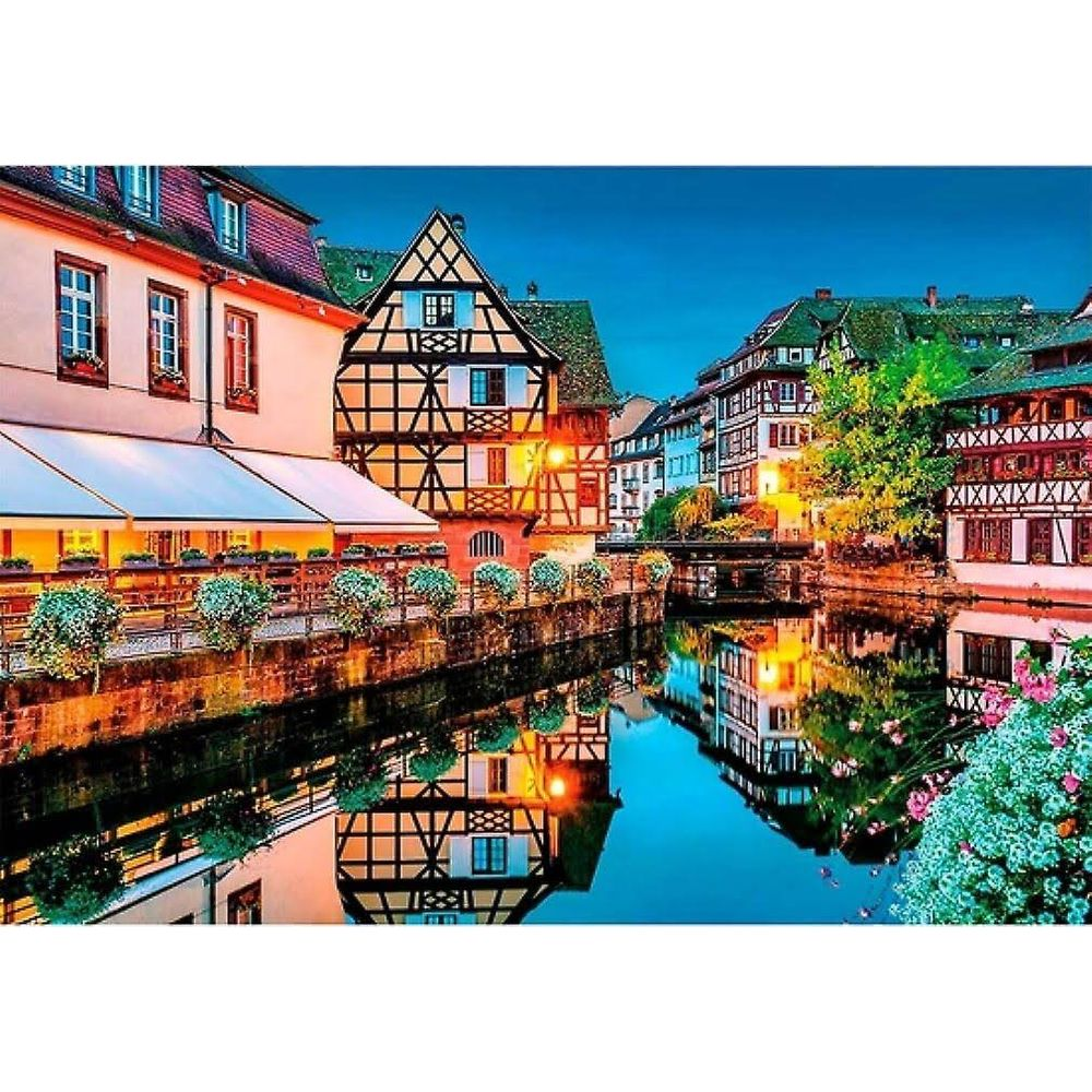 Domy z muru pruskiego wzdłuż kanału z odbiciami w wodzie o zmierzchu.