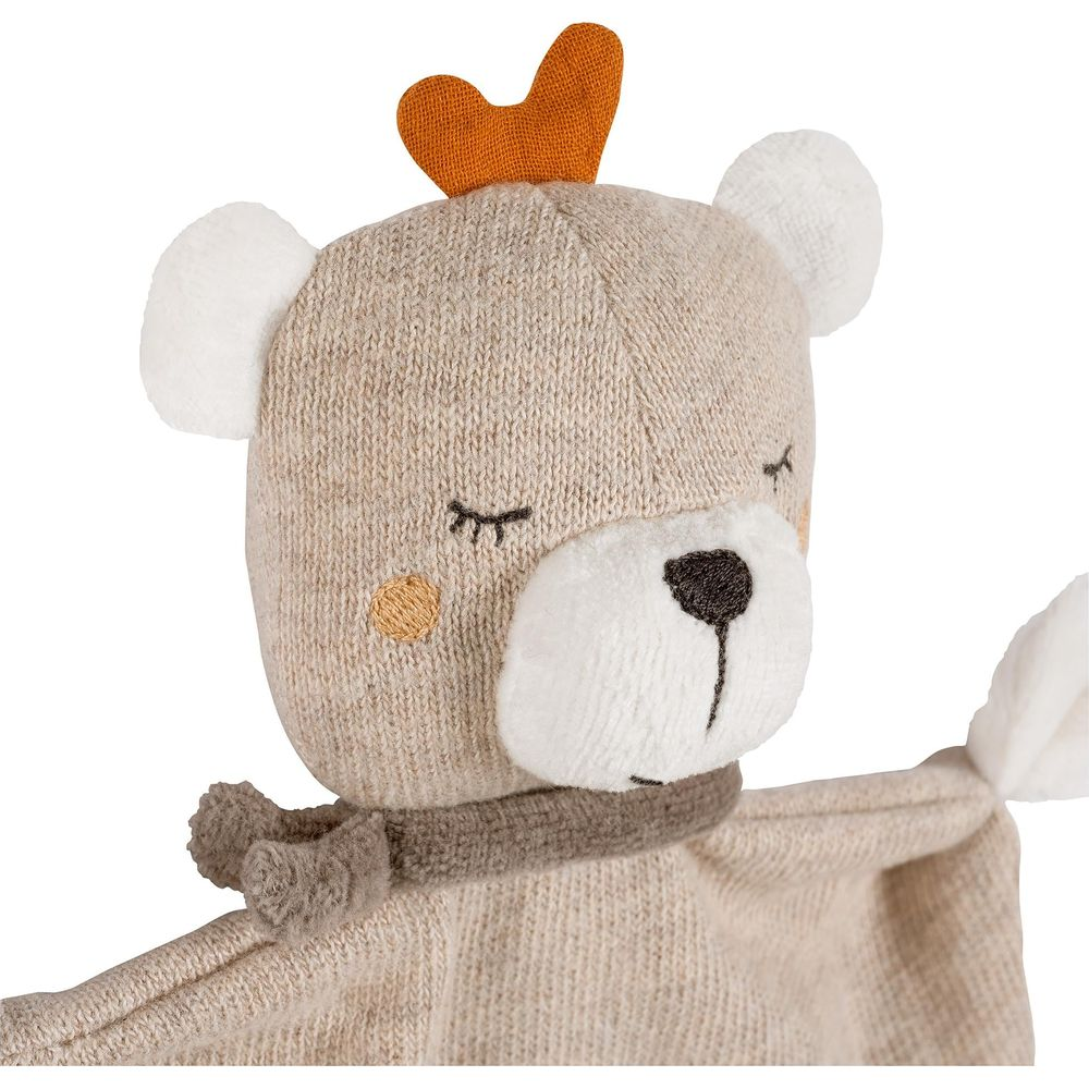 Un orsacchiotto di peluche lavorato a maglia con corna arancioni e sciarpa.
