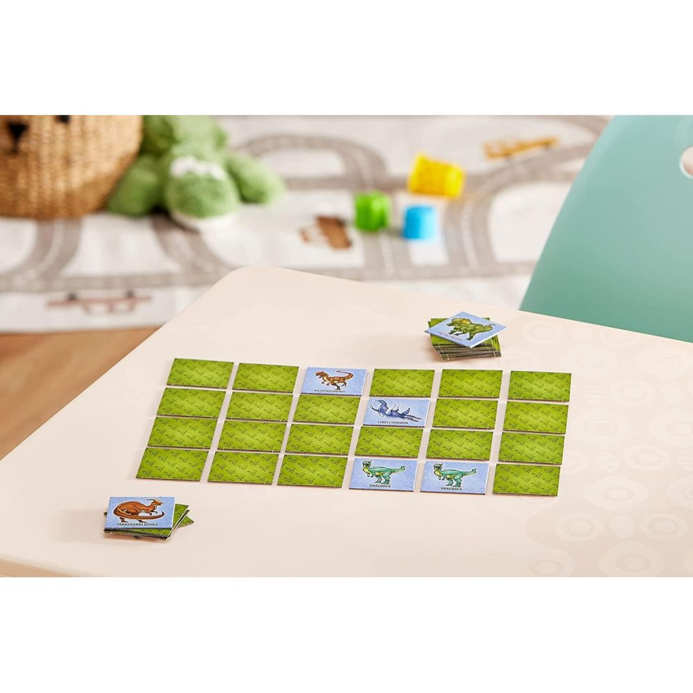 Dinosaurier-Gedächtniskartenspiel auf einem Tisch mit Spielzeug im Hintergrund.