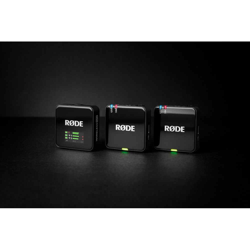 Tre trasmettitori neri Rode Wireless GO II su superficie scura. Uno ha uno schermo.