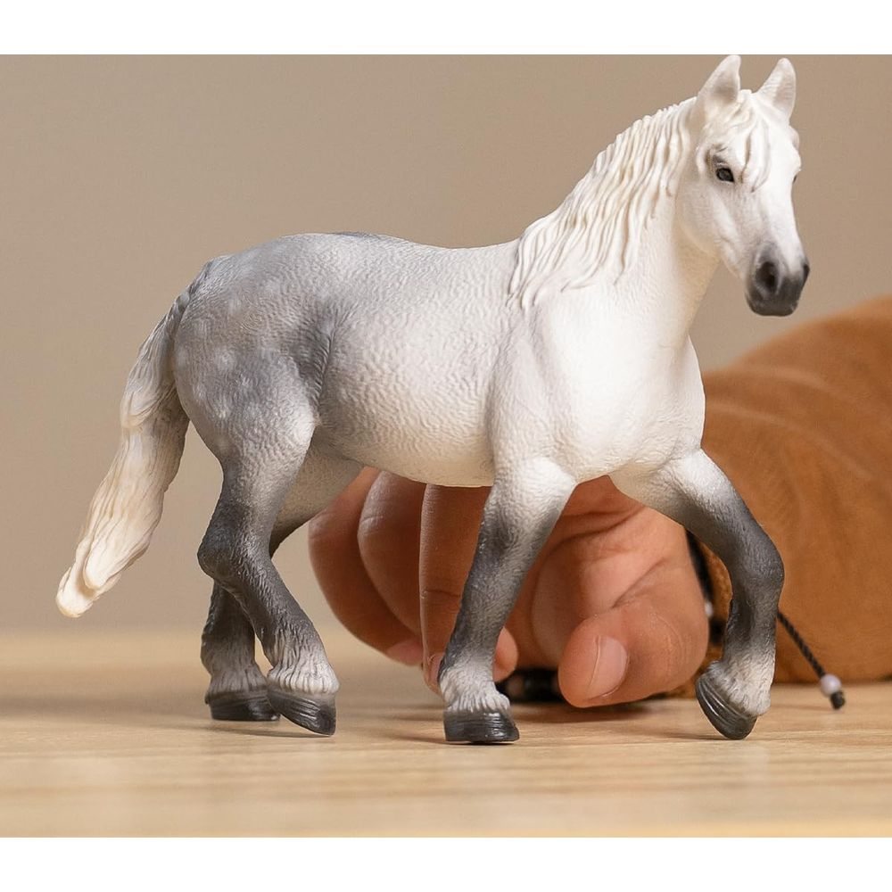 Biały posąg konia z szarym, nakrapianym ciałem stoi na drewnianym stole.