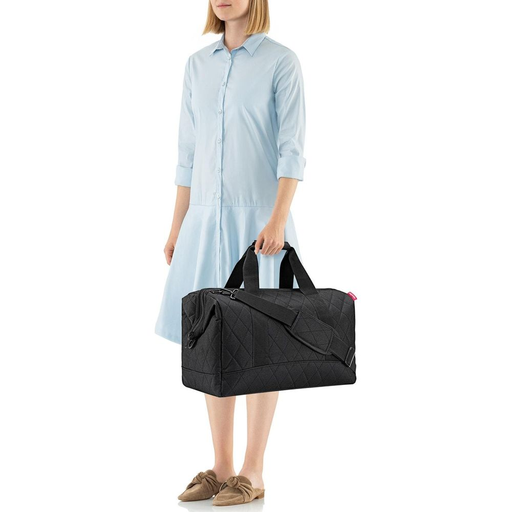Mujer con bolso de lona negro acolchado, vestido azul claro.
