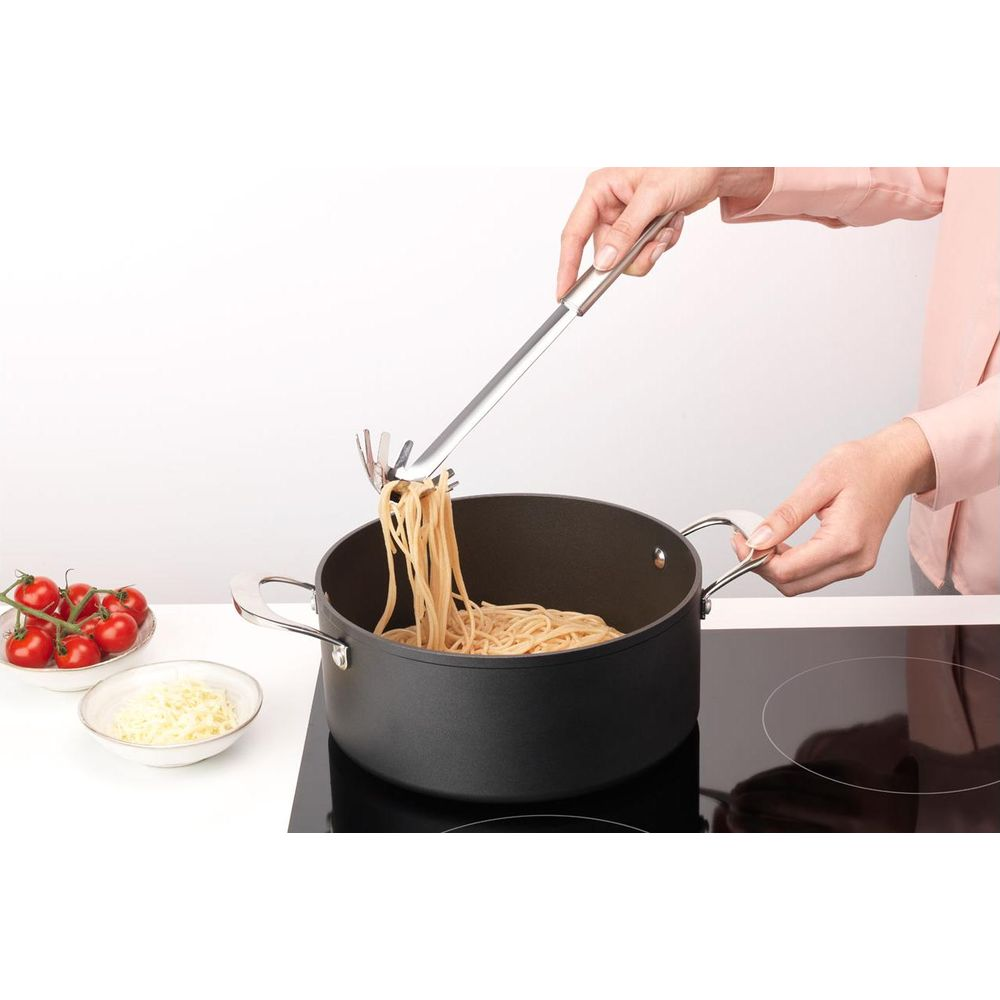 Eine Person hebt mit einer Nudelzange Spaghetti aus einem Topf.