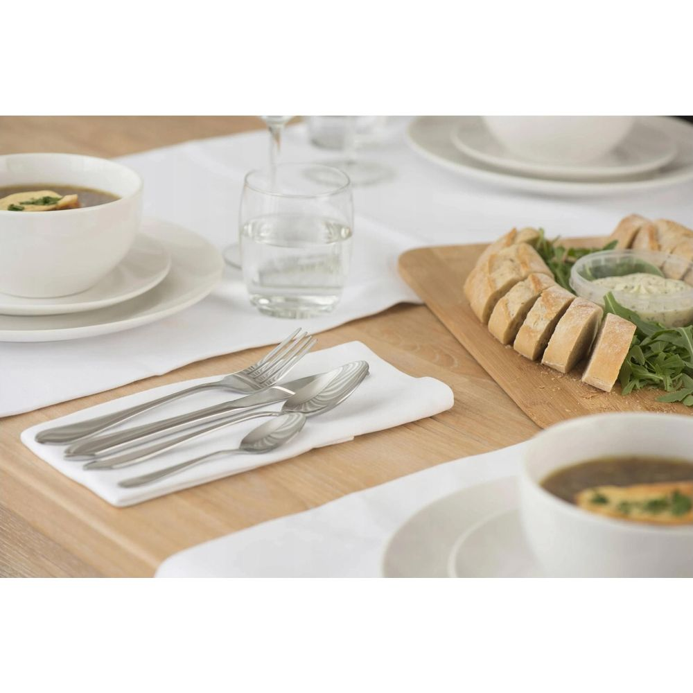 Set table with soup, bread, dips, and cutlery on a white napkin.