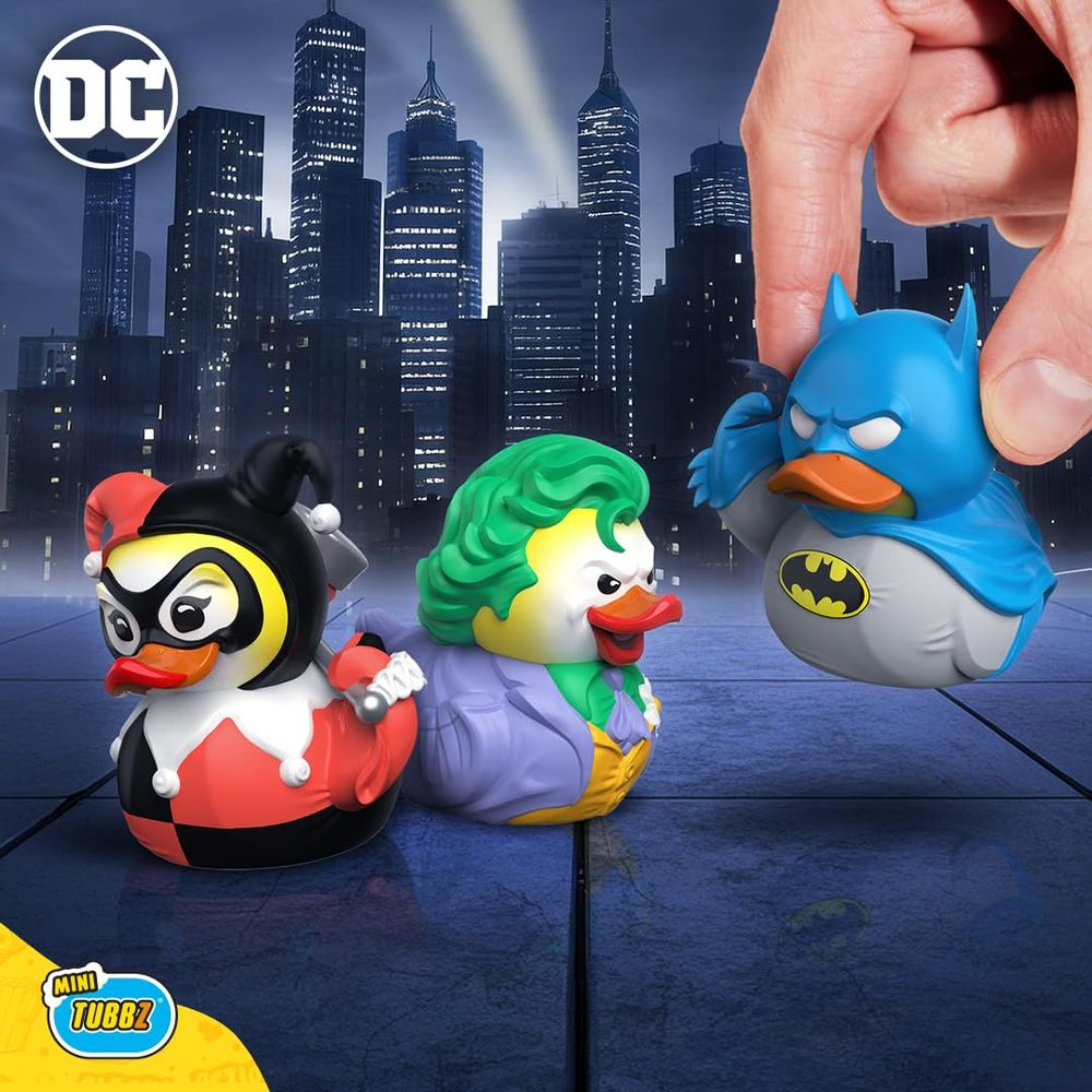 Batman, Joker und Harley Quinn Quietscheentchen vor einer Stadtsilhouette.