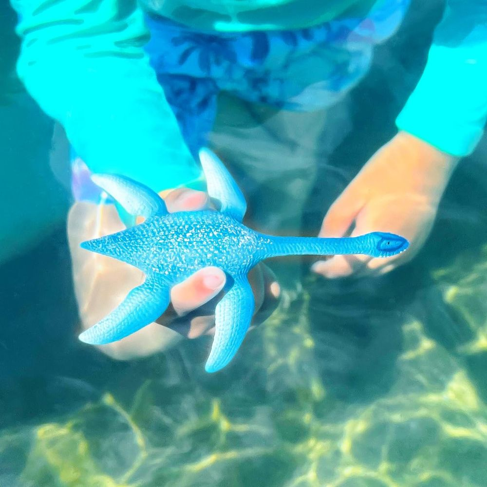 Dziecko trzyma pod wodą niebieską zabawkę - plezjozaura.