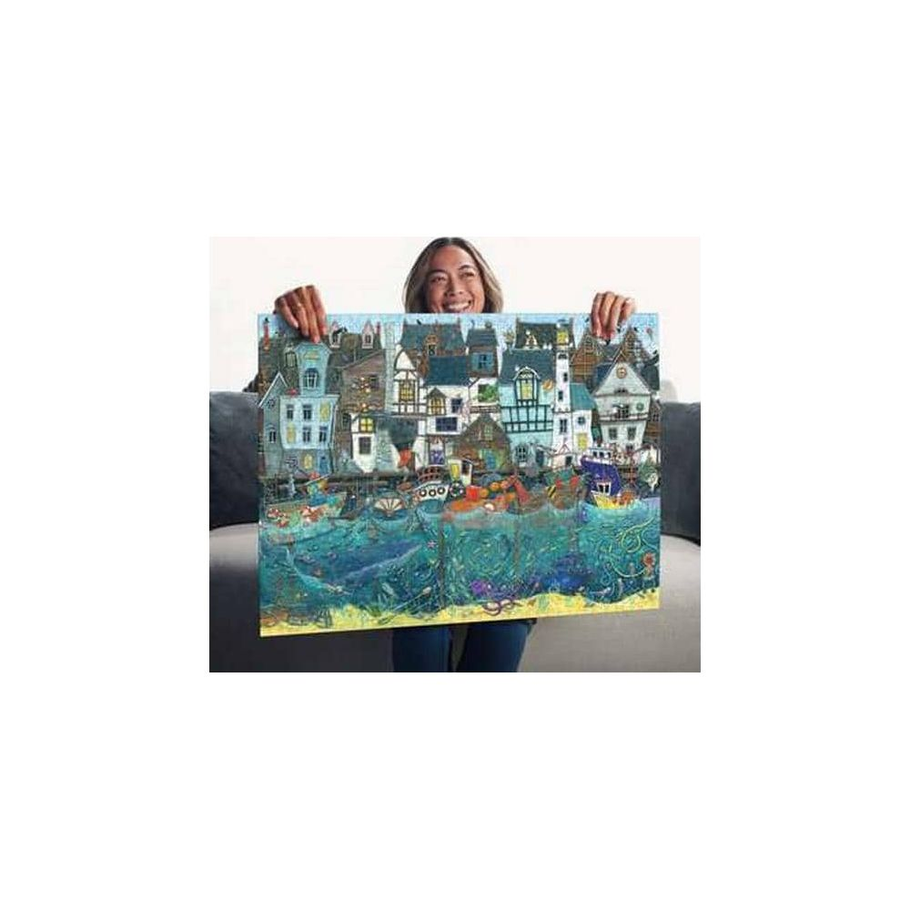 Una donna tiene un quadro di una città costiera con case e barche sull'acqua.