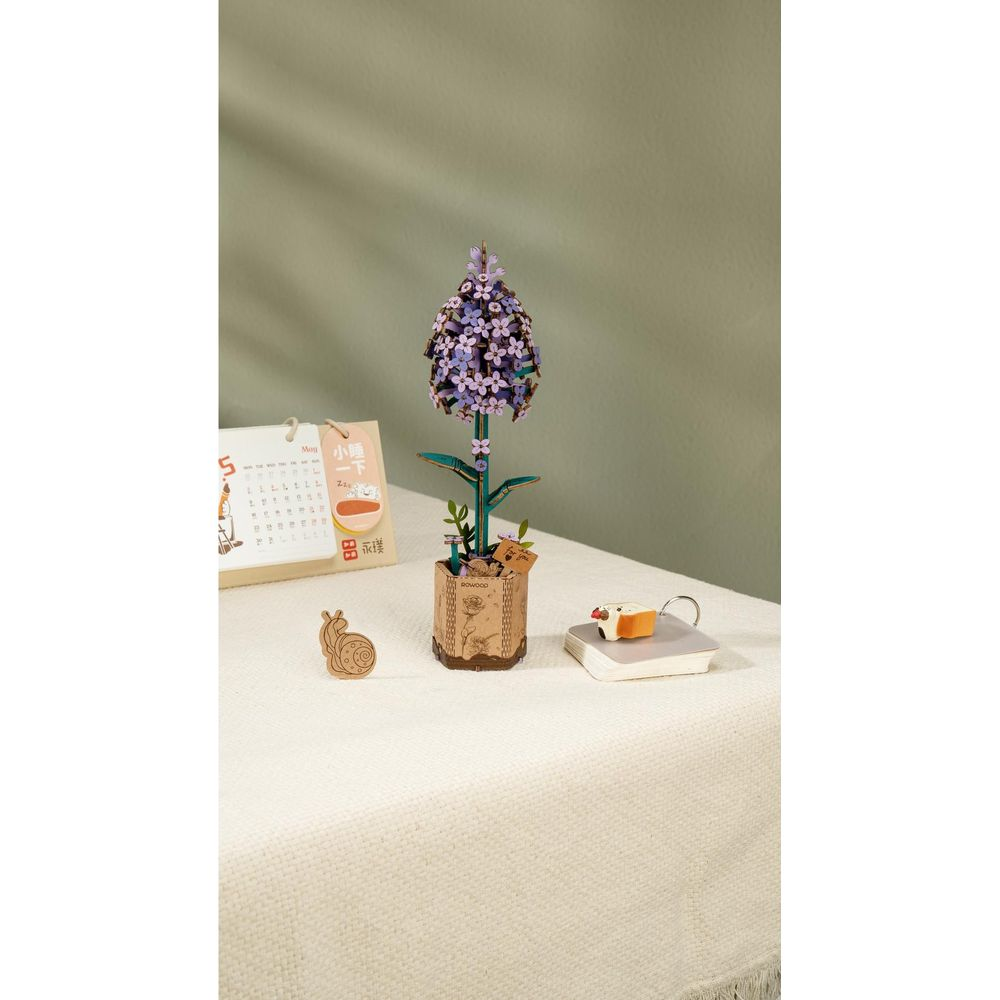 Drewniana budowla niebieskich kwiatów z kalendarzem, ślimakiem i książką.